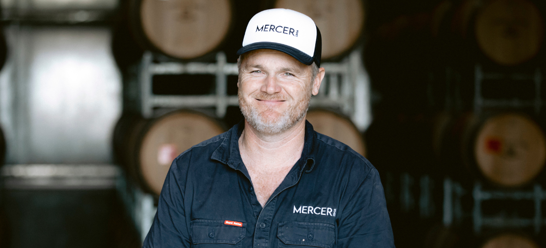 A man smiling surrounded by barrels 